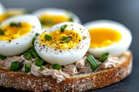 Open sandwich with soft boiled eggs, tuna and fresh herbs on rustic bread slice. Healthy breakfast or lunch meal with protein rich ingredients.