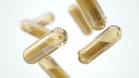 Transparent yellow gel capsules scattered on white background, pharmaceutical supplements for health and wellness medicine isolated.