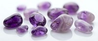 Collection of polished amethyst gemstones in various cuts and sizes displaying rich purple hues on white background for jewelry design and luxury accessories.