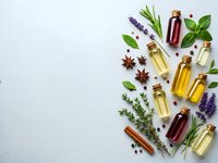 Natural essential oil bottles with fresh herbs lavender rosemary basil and spices on white background for aromatherapy wellness and organic skincare products.