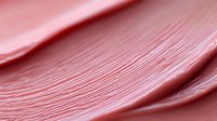 Close-up of smooth pink cosmetic cream texture with fine lines and ridges, showing luxurious skincare product consistency for beauty and wellness applications.