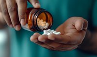 Pills pouring from amber prescription bottle into African American hands against teal medical background, dramatic lighting highlights medication and healthcare concept.