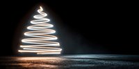 Light painting Christmas tree created with long exposure photography on dark background with illuminated ground surface for holiday designs.