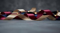 Elegant burgundy and gold satin ribbons flowing gracefully across dark surface creating luxurious decorative arrangement for gift wrapping and crafting projects.