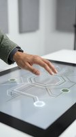 Male hand touching interactive digital touchscreen display with futuristic interface elements and geometric patterns in modern office environment.