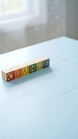 Wooden alphabet blocks spelling CHANGE on light blue surface with soft natural lighting and blurred background for business transformation concepts.