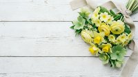 Fresh yellow spring bouquet with ranunculus and daffodils on white wooden background, flat lay with copy space for greeting cards.