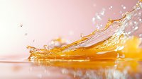 Orange liquid splash creating dynamic crown formation with droplets against soft pink background, high-speed macro photography capturing fluid motion and light reflection.