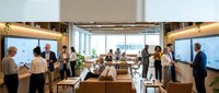 Modern corporate boardroom with diverse business professionals during meeting presentation with large windows and contemporary furniture.