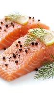 Fresh salmon fillets with dill, lemon slices and black peppercorns on white background ready for cooking or gourmet meal preparation.