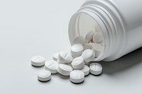 White pharmaceutical tablets spilling from prescription medicine bottle on light background, medical and healthcare concept for pharmacy advertising.