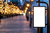 Empty white mockup billboard on street lamp post with blurred festive bokeh lights and illuminated pathway at dusk, copy space for advertising.