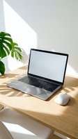 Modern laptop with blank screen on wooden desk beside monstera plant in bright sunlit home office workspace for remote work and productivity.