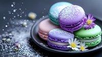 Colorful French macarons in purple, green, and pink on dark plate decorated with small daisies and sugar powder, moody food photography with bokeh effect.