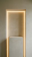 Minimalist concrete niche with warm LED strip lighting and a plaster pedestal, creating an elegant product display backdrop.