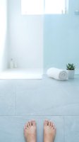 Modern bathroom interior with male feet on tiled floor, white towel and succulent plant creating spa-like atmosphere for wellness and self-care concepts.