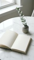 Open blank notebook on a marble table with a eucalyptus sprig in a ceramic vase, soft natural light, minimal home decor styling.