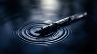 Metallic pen resting on concentric water ripples, creating circular waves in dark blue liquid surface for creative writing and design concepts.
