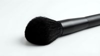Soft black powder makeup brush with fluffy bristles on a white background, isolated for beauty, cosmetics, and professional makeup artist use.