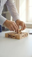 Businessman hands placing wooden cube with directional arrows on desk representing strategic planning and decision making in corporate environment.