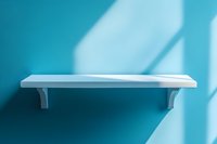 White empty shelf mounted on turquoise wall with soft window light and shadows creating minimal contemporary composition for product display.