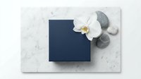Navy blue gift box on marble surface with white orchid flower and zen stones, elegant flat lay for luxury branding and product presentation.
