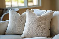Elegant chevron patterned throw pillows on beige sofa in bright living room interior with natural window light for home decor and furniture styling.