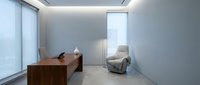 Modern minimalist office interior with wooden desk, gray armchair and clean white walls for contemporary workspace design.