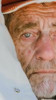 Mature Caucasian male with gray beard and weathered facial features wearing brown cowboy hat, close-up portrait against white background for western character design.