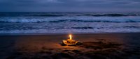 Romantic beach bonfire glowing at twilight with ocean waves and purple sky creating peaceful evening atmosphere for couples and relaxation.