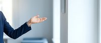 Close-up of businessman's open palm gesture in modern office setting, conveying welcome, agreement, or presentation concept for corporate communication.