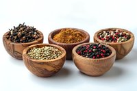 Aromatic spices and peppercorns collection in wooden bowls on white background, featuring colorful mix of black, rainbow, and green peppercorns with ground turmeric for cooking and seasoning.