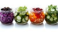 Colorful variety of fermented vegetables in glass jars with cabbage, cucumber, carrots and herbs. Healthy probiotic food for gut health and immunity.