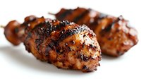 Grilled chicken drumsticks with crispy caramelized skin and herbs on white background. Barbecue poultry legs with golden brown seasoning for cooking recipes.