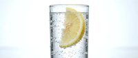 Glass of sparkling water with fresh lemon slice and ice bubbles, isolated on white background for beverage, refreshment, and drink design projects.
