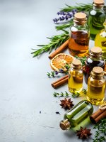 Natural essential oils in glass bottles with herbs, spices and dried citrus on textured background for aromatherapy, wellness and spa treatments.