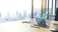 Modern office workspace with holographic financial growth chart display showing upward trending data analytics on transparent screen with city skyline background.
