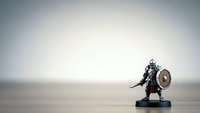 Medieval knight miniature figurine with sword and shield standing on wooden surface against neutral background for tabletop gaming and collectibles.