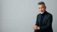 Mature Hispanic male professional in dark blazer and black shirt against neutral background, suitable for corporate portraits, business websites, and professional headshots.