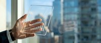 Close-up of hand holding transparent glass panel with city skyline reflection, representing technology innovation and future digital solutions for business applications.