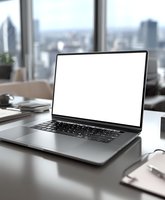 Modern laptop with blank white screen on office desk with panoramic city skyline view through large windows, perfect for business presentation mockup.