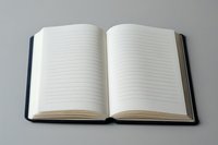Open blank lined notebook with navy blue hardcover lying on gray background, pages spread wide to show empty ruled paper ready for writing or journaling.