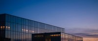 Young professional woman with South Asian ethnicity wearing business attire working at modern glass office building during twilight hours for corporate, finance, and business concepts.