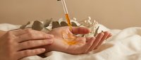Hands cupped receiving golden honey dripping from wooden dipper against warm beige background. Natural skincare and wellness concept for spa treatments.