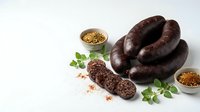 Traditional blood sausage with spices and herbs on white background. Homemade black pudding sliced showing texture. Artisanal charcuterie product.