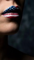 Close-up of woman's lips painted with American flag design featuring stars and stripes in red white and blue for patriotic makeup concept.