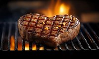 Juicy grilled beef steak with grill marks cooking over open flames. Perfectly seared meat with caramelized exterior showcases gourmet barbecue preparation.