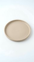 Empty beige ceramic plate on white background, suitable for food styling, product photography, tableware design, and culinary presentations.