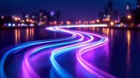 Glowing neon light trails curve along waterfront at night, creating luminous blue and purple streaks against dark cityscape with reflections on water surface.
