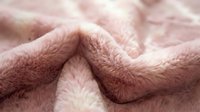 Soft pink fluffy blanket with cozy texture creating warm comfortable folds for home decor and relaxation concepts.